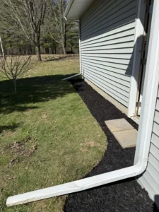 Fresh black mulch laid along a house foundation in early spring before the lawn greens up