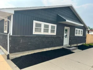Black mulch bed running along a stone skirted foundation and around the corner of the building