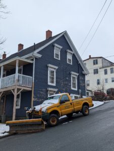 Pickup truck fitted with a plow blade clearing snow on a residential street