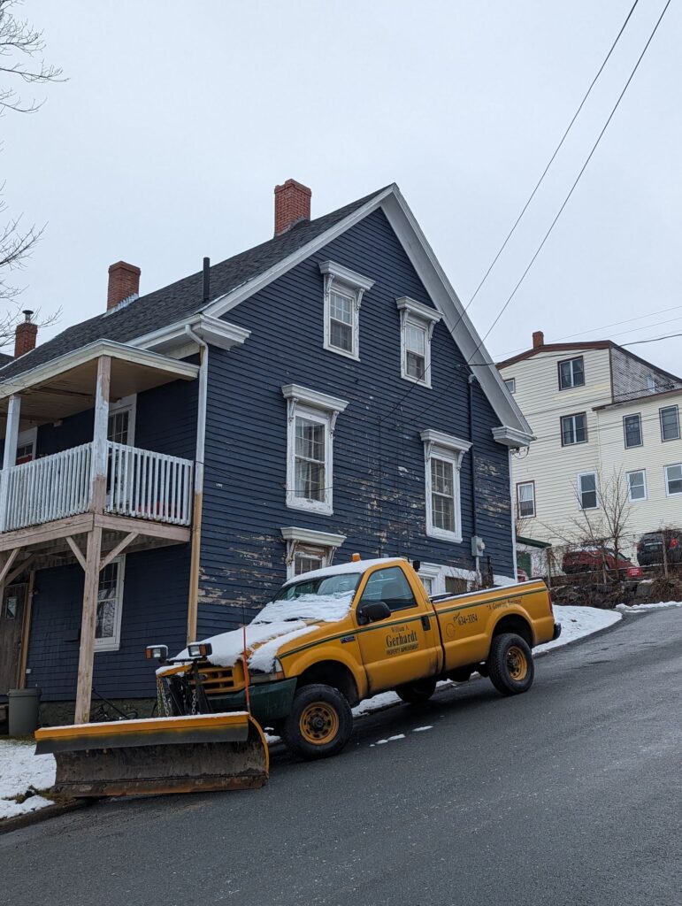 Pickup truck fitted with a plow blade clearing snow on a residential street