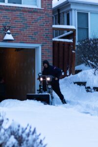 Clearing a residential driveway with a snow blower after an overnight storm