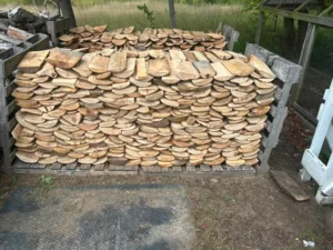 Rows of split hardwood stacked and seasoning outdoors before firewood delivery